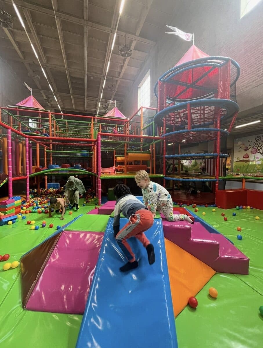 Kinderen klimmen en spelen in een grote binnenspeeltuin