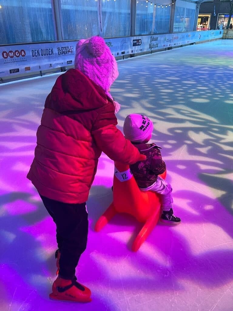 Schaatsen met een schaatshulp op een ijsbaan vol gekleurd licht
