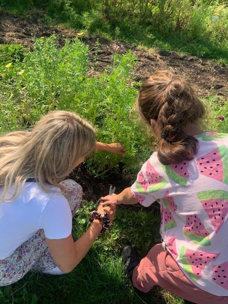 Een begeleider en een kind plukken samen in de tuin